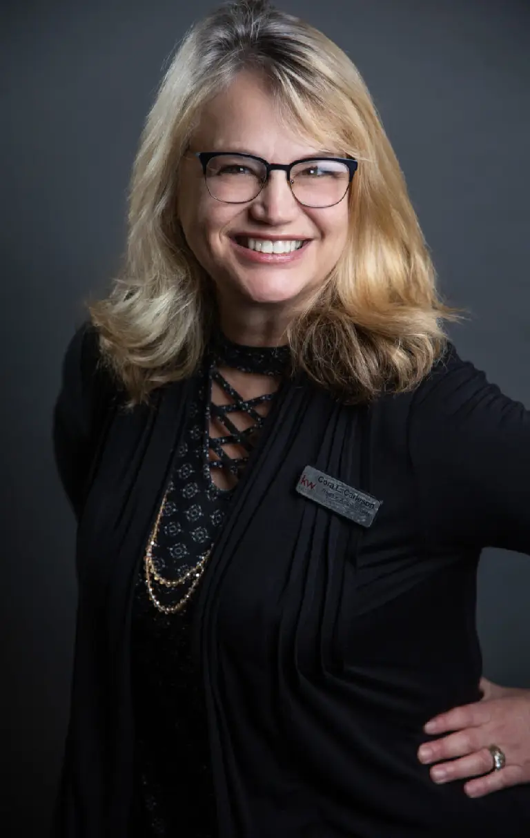 A woman with blonde hair and glasses smiling.