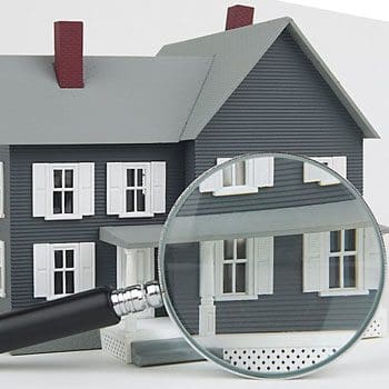 A magnifying glass is on top of a model house.