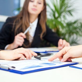 A woman is sitting at a table with papers.