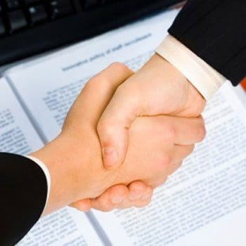 Two people shaking hands over a book