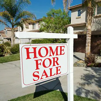 A home for sale sign in front of some houses.