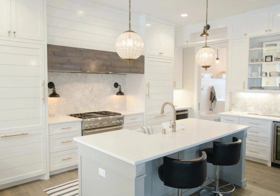 A kitchen with white cabinets and black stools.